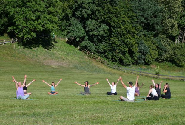 Yoga-Gruppe bei einer gemeinsamen Übung auf der Wiese